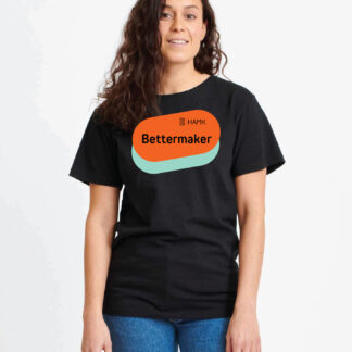 Musta t-paita. Paidan yläosassa on oranssinvärinen soikionmallinen kuva, jonka alta näkyy turkoosia soikiota. Oranssin osan päällä on musta HAMK logo ja Bettermaker-teksti.